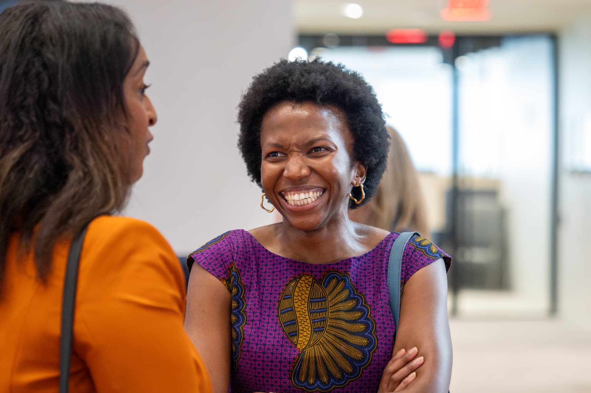 Woman in a purple patterned dress laughing during a conversation at the event
