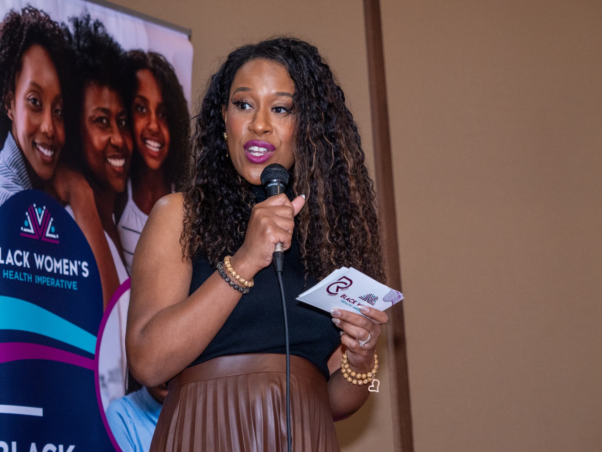 Speaker with a microphone and note cards at a Black Women's Health Imperative event