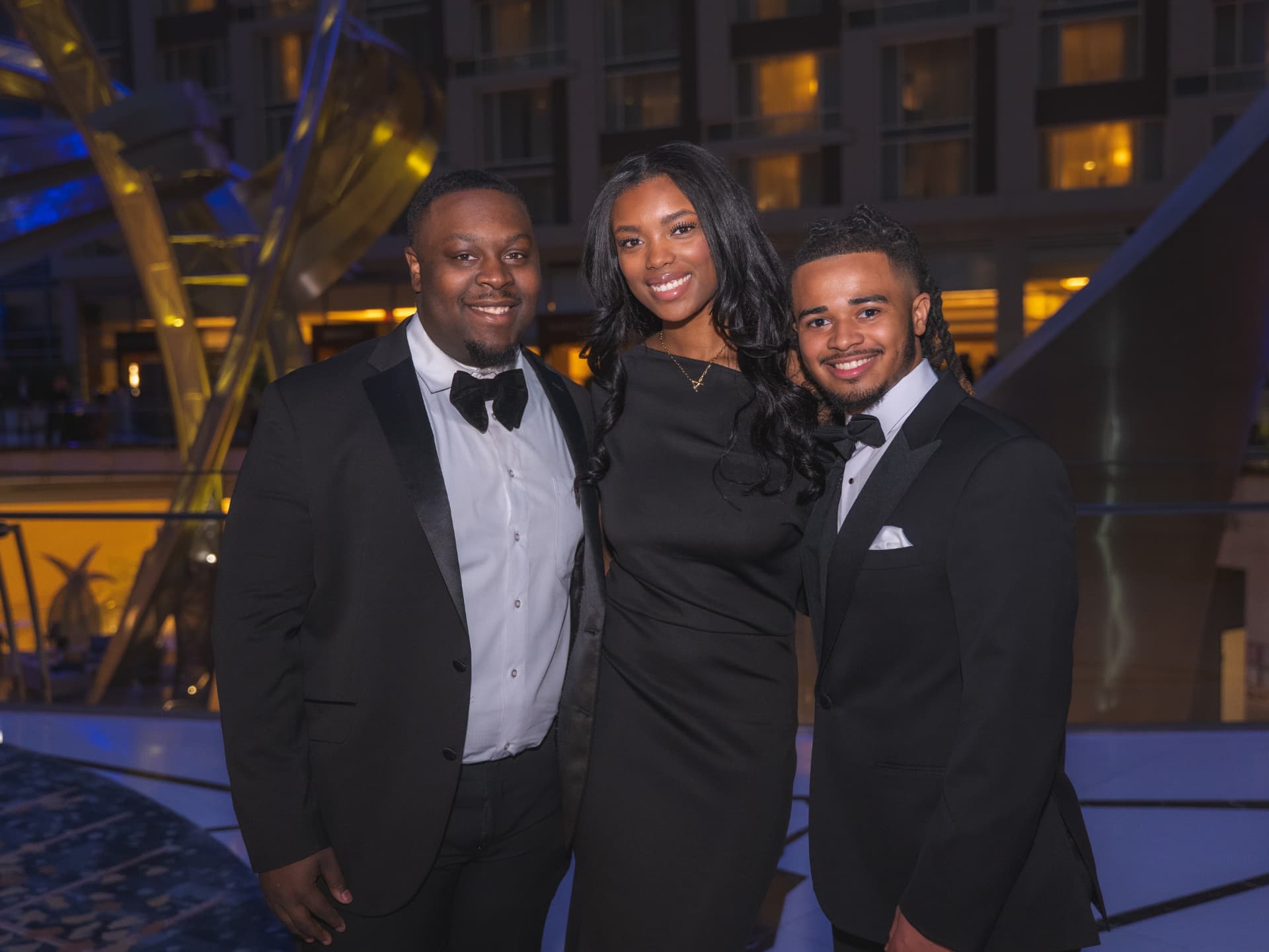 Three young guests in black tie posing together at the reception