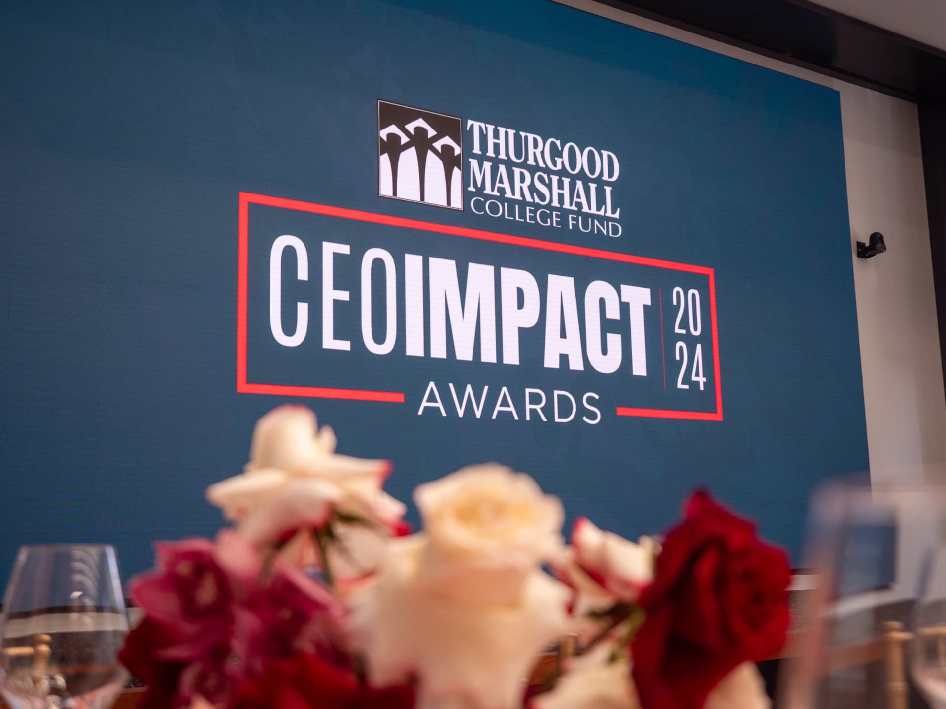 CEO IMPACT Awards screen above a table of roses and wine glasses