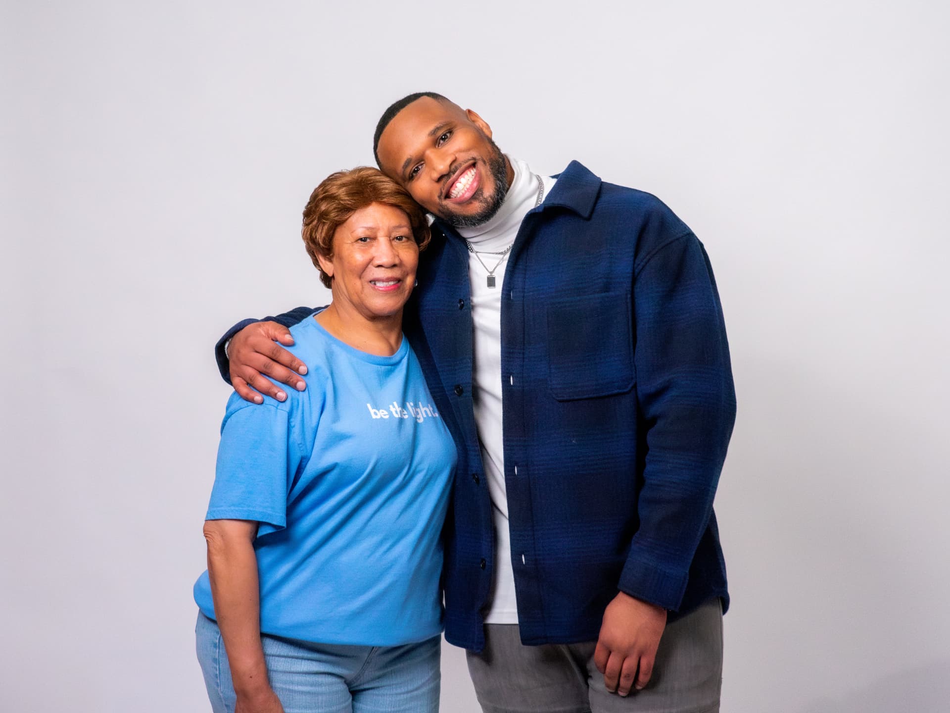 Two people posing arm in arm in a bright studio portrait