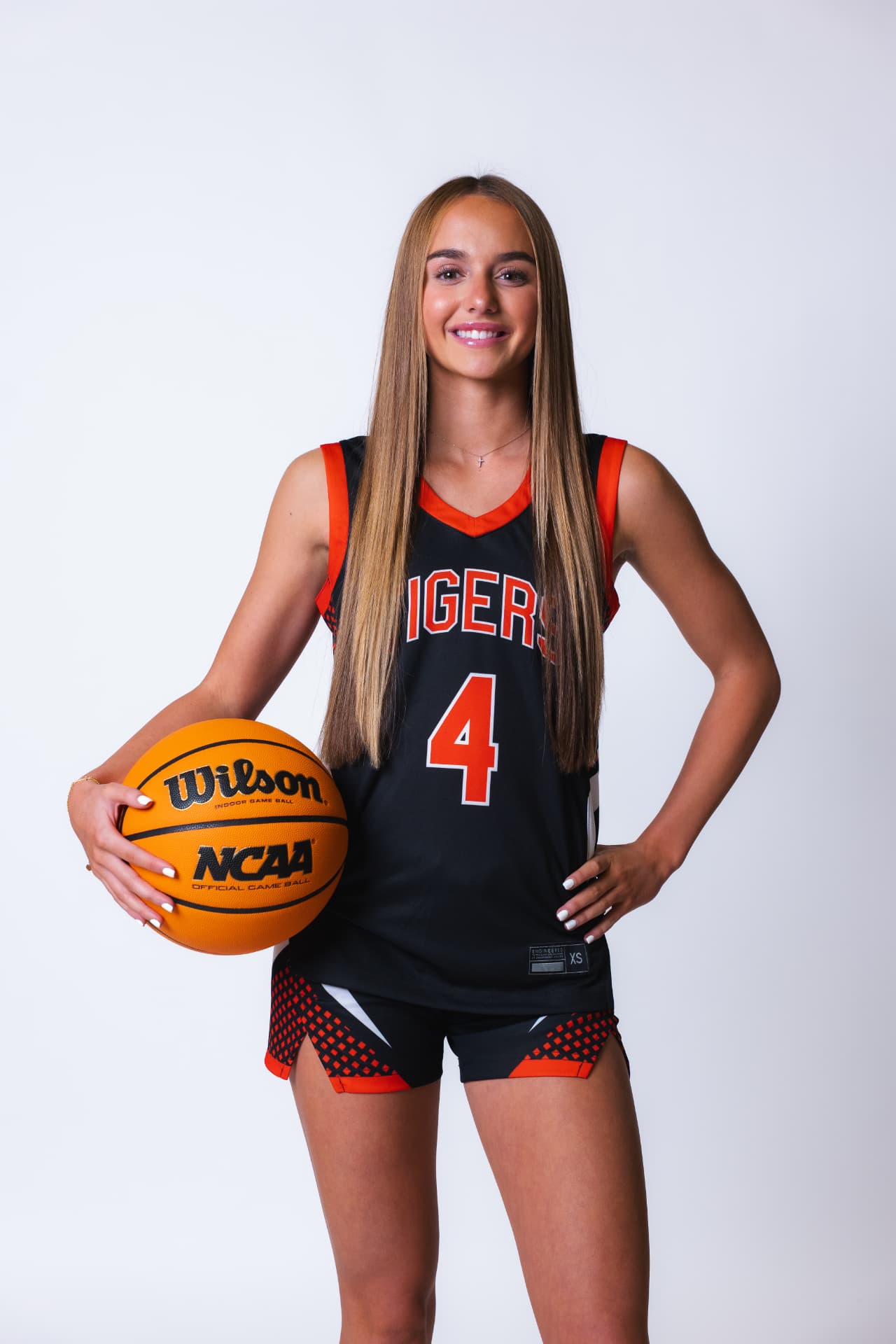 Basketball player in a number 4 Tigers jersey holding a basketball on a white backdrop