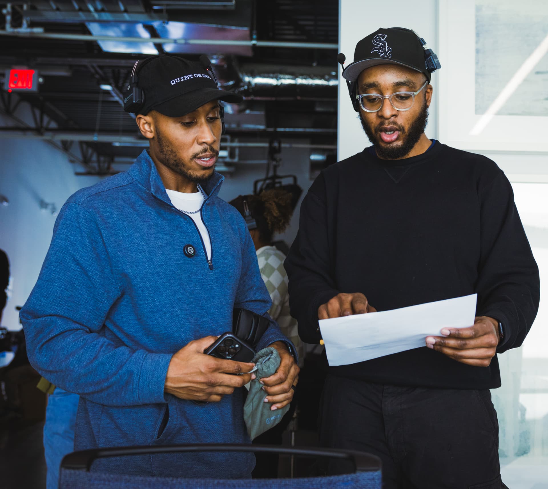 Two crew members in headsets reviewing a run-of-show script on set
