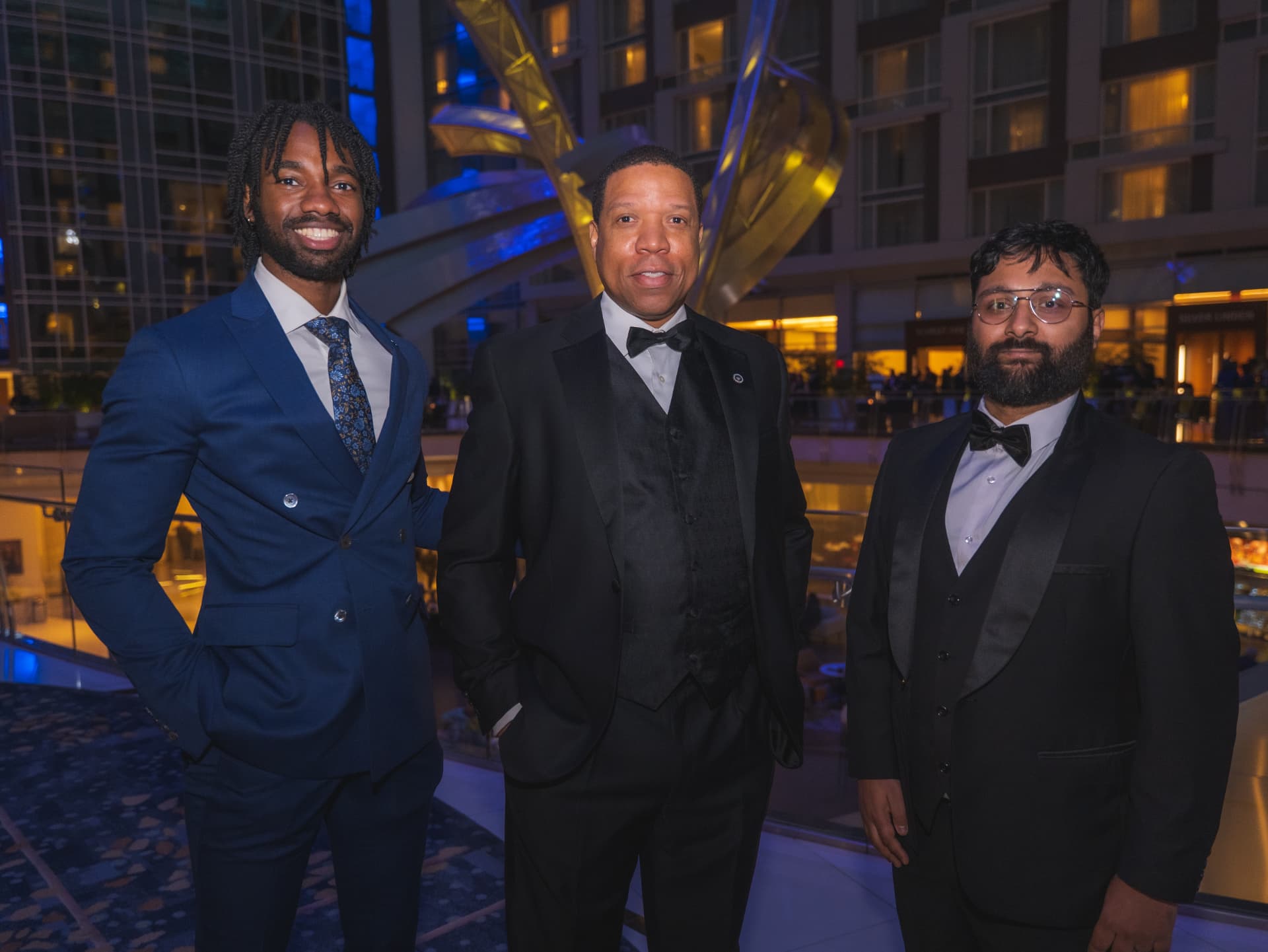 Three guests in formalwear posing in the atrium during cocktail hour