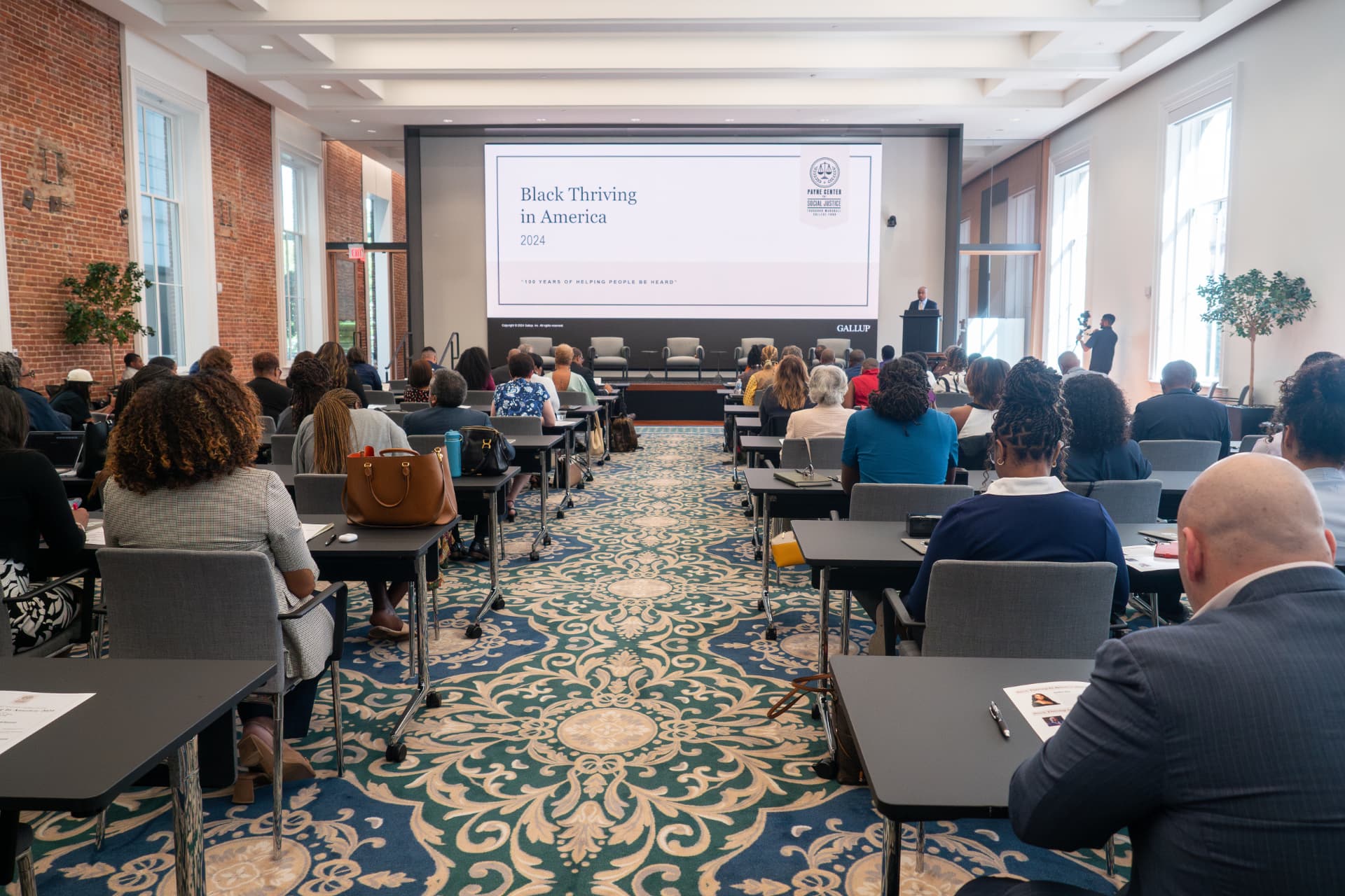 Wide view of a conference hall with a Black Thriving in America presentation on screen
