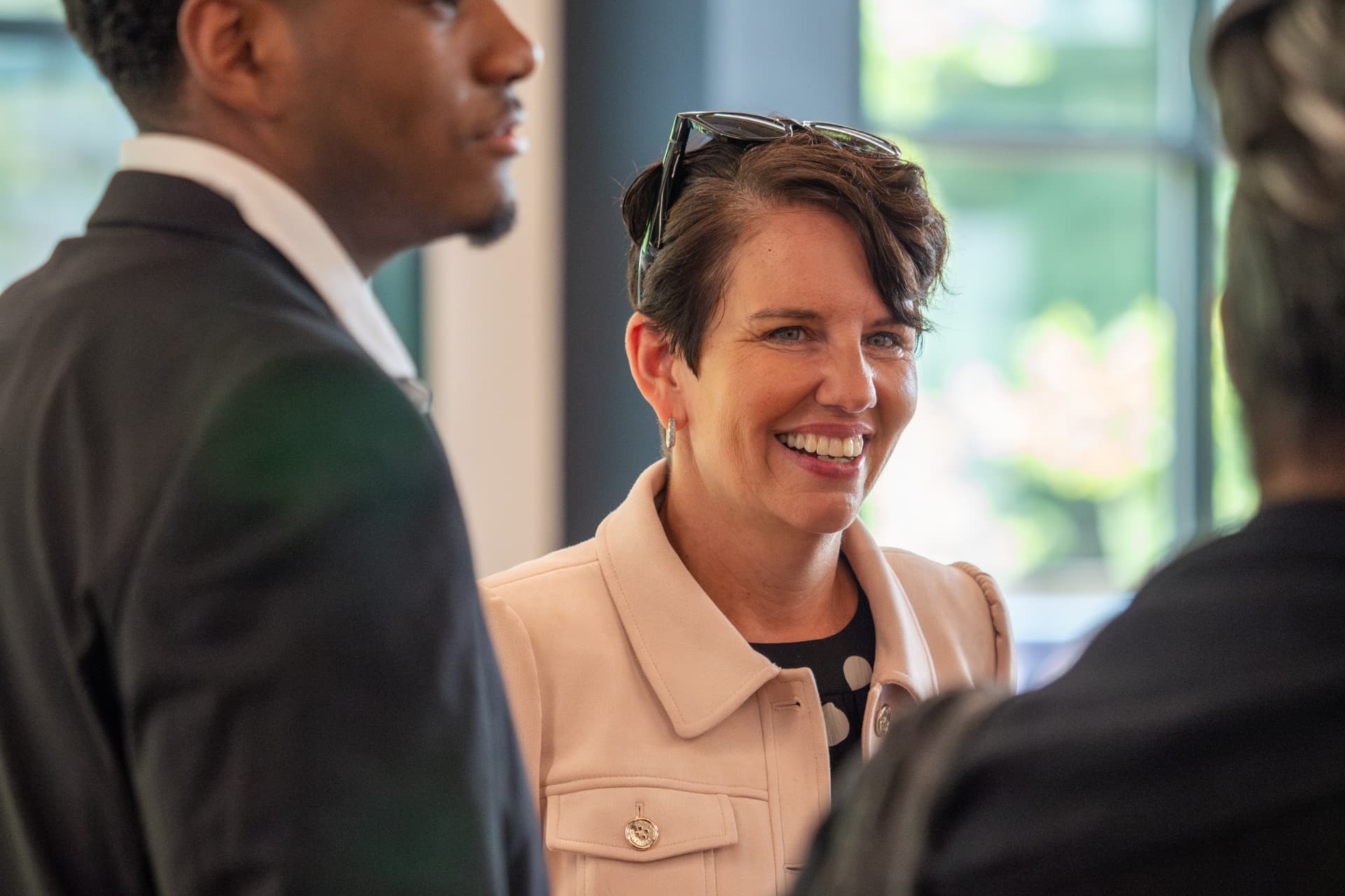 Woman with sunglasses on her head laughing mid-conversation at a networking event