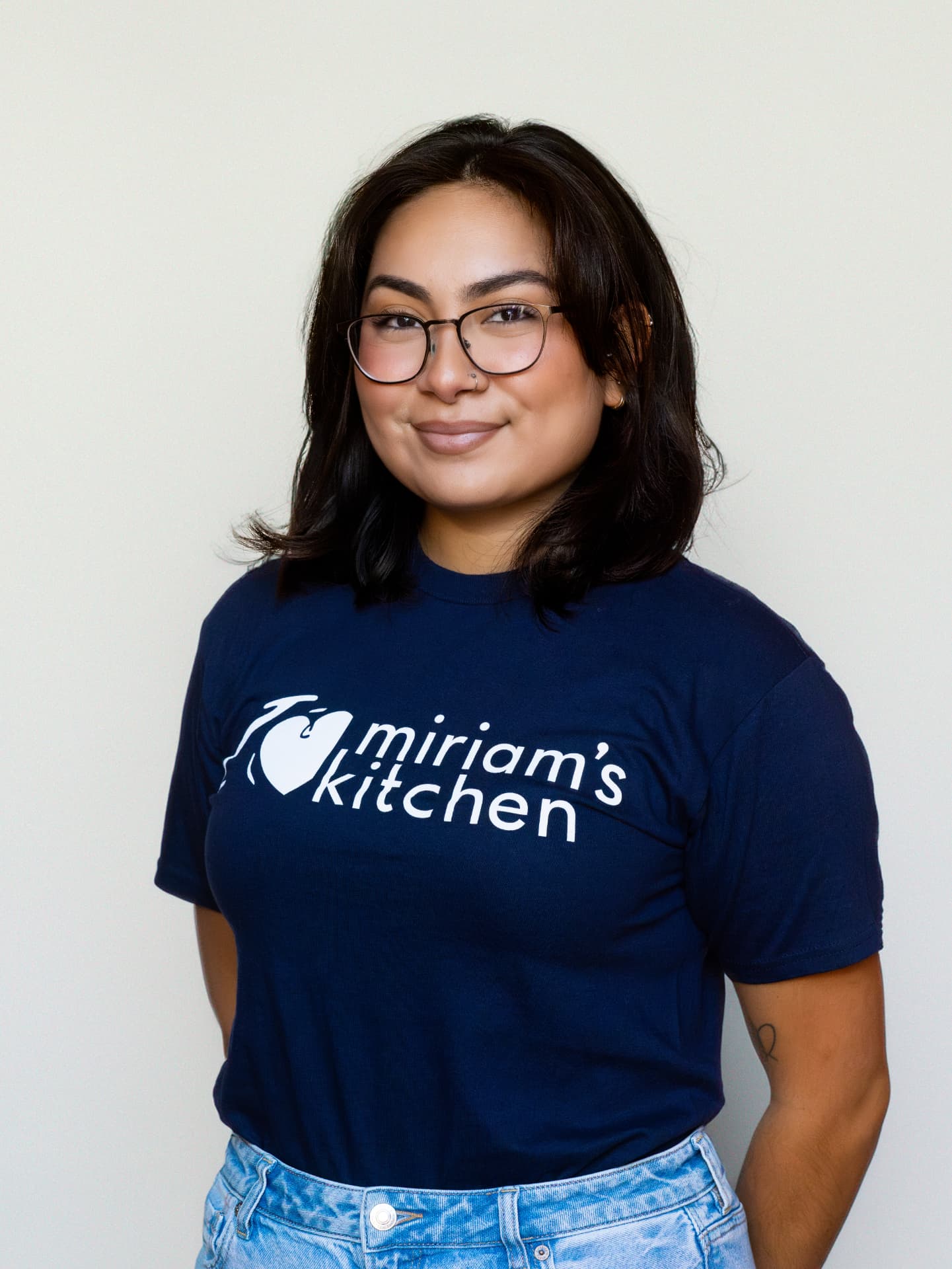 Team member in a navy organization shirt in a studio headshot