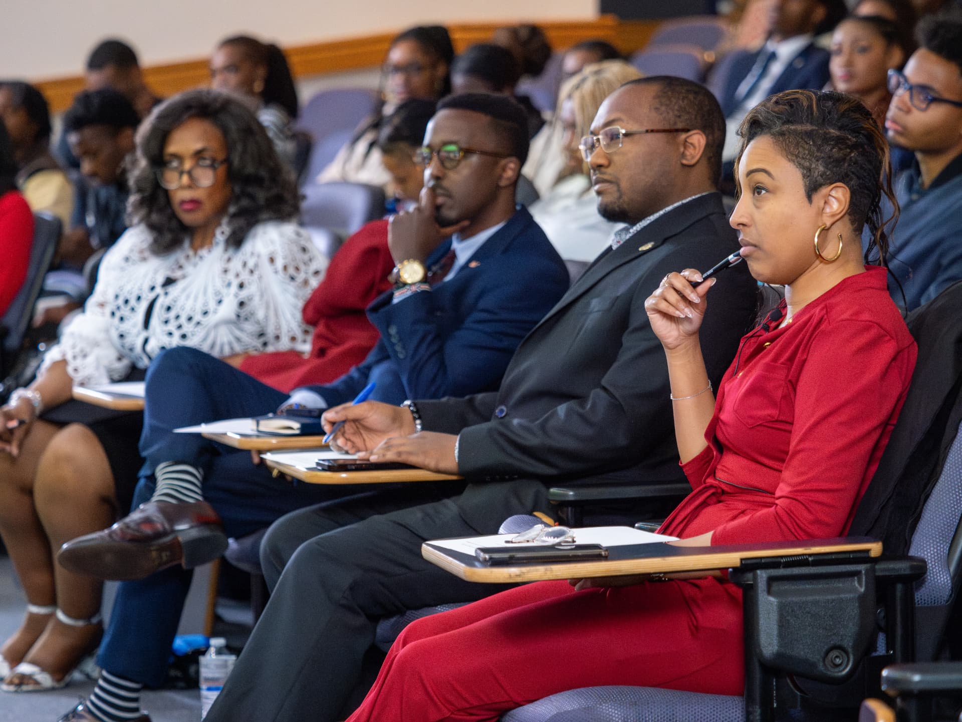 Audience members taking notes during a lecture-hall presentation