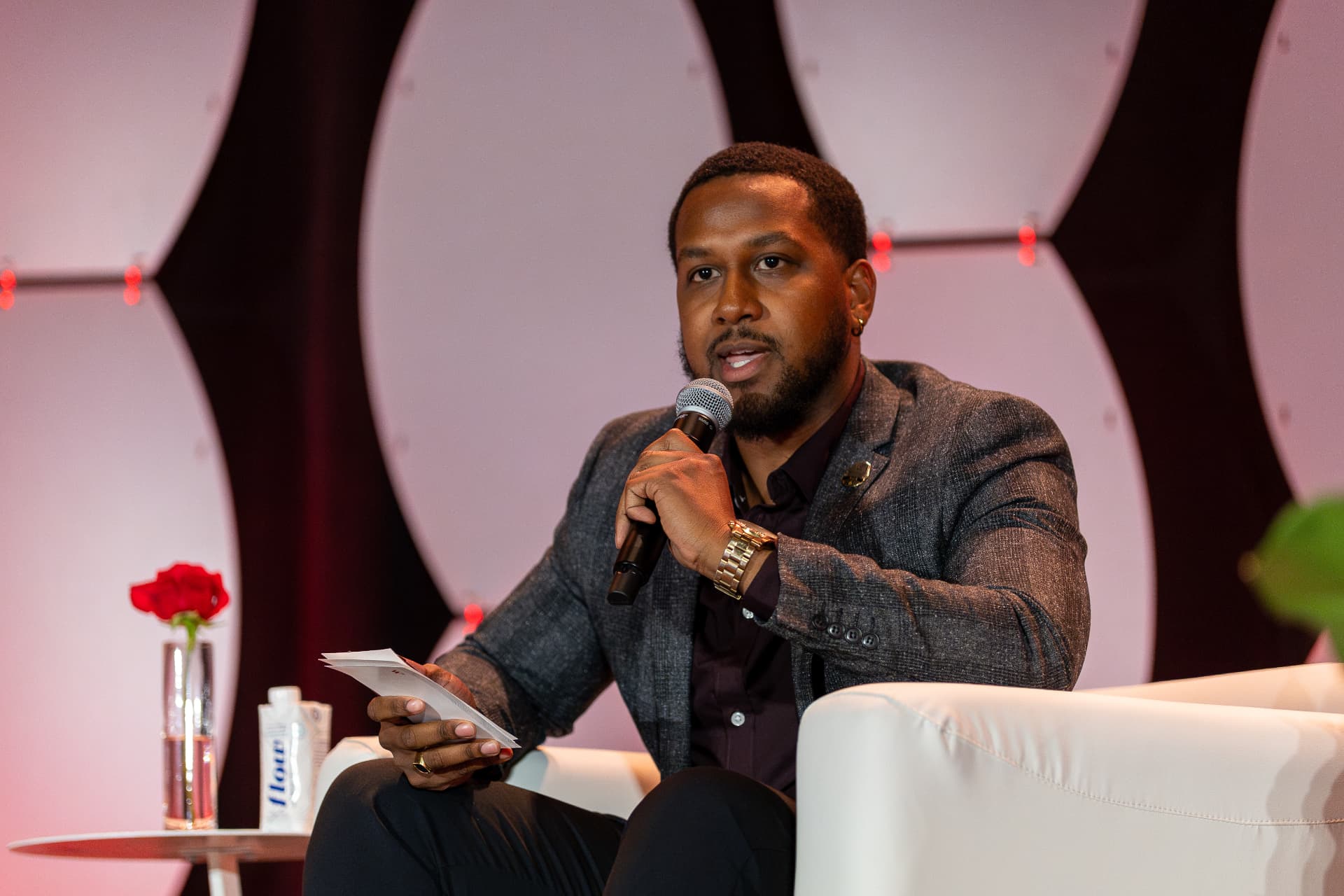 Moderator with a microphone and note cards speaking during a panel discussion