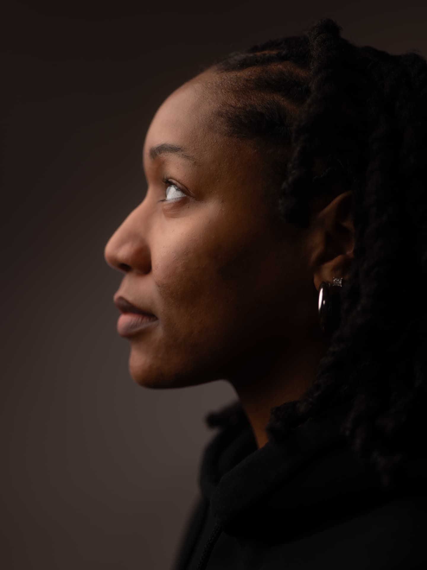Dramatic side profile of a woman with locs in low-key studio lighting
