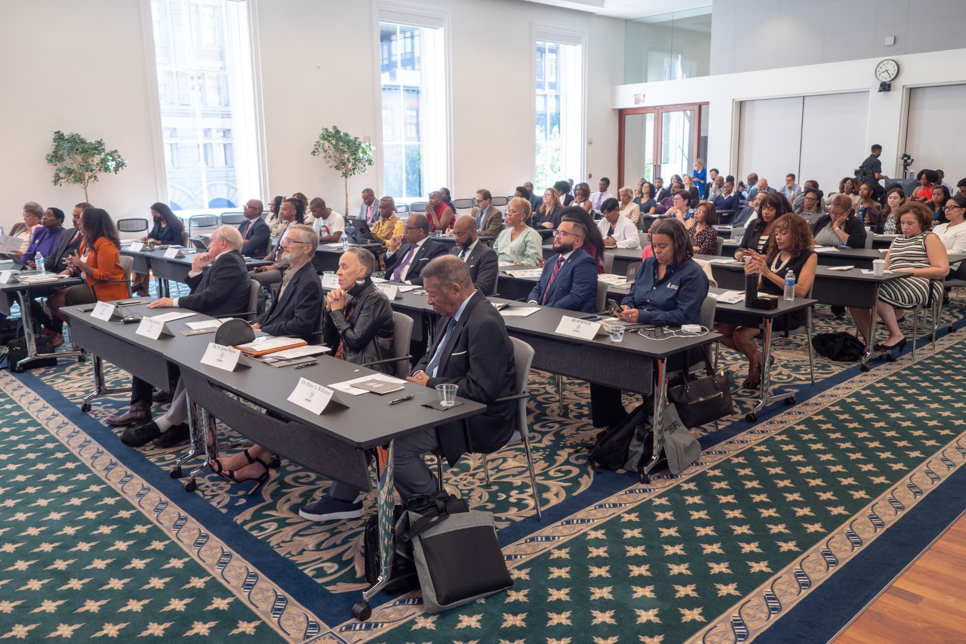 Audience seated at long tables during a conference session