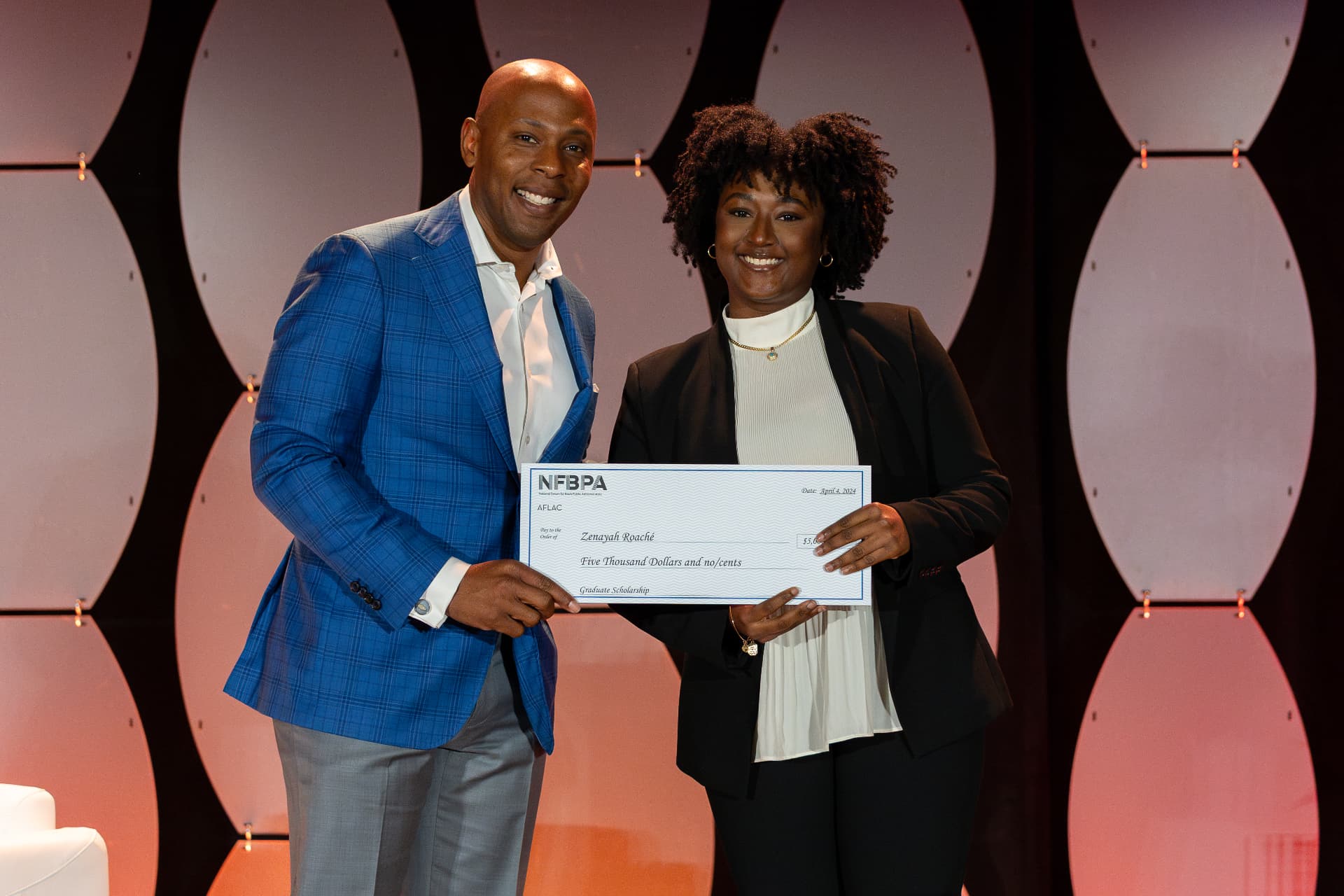 Scholarship recipient receiving a five thousand dollar NFBPA check on stage