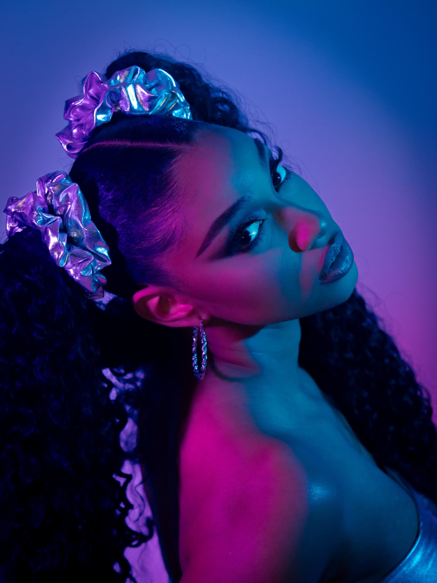 Beauty portrait lit in pink and teal with metallic hair accessories