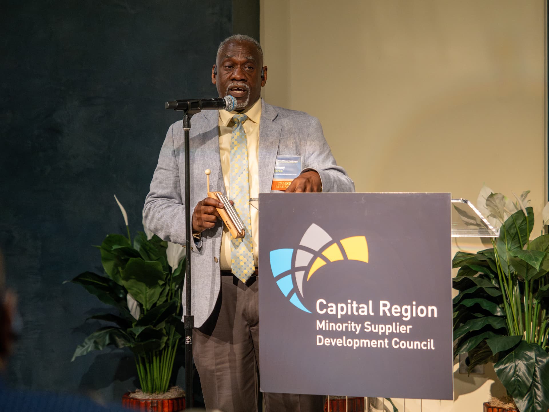 Speaker holding a chime at the podium beside the Capital Region Minority Supplier Development Council sign