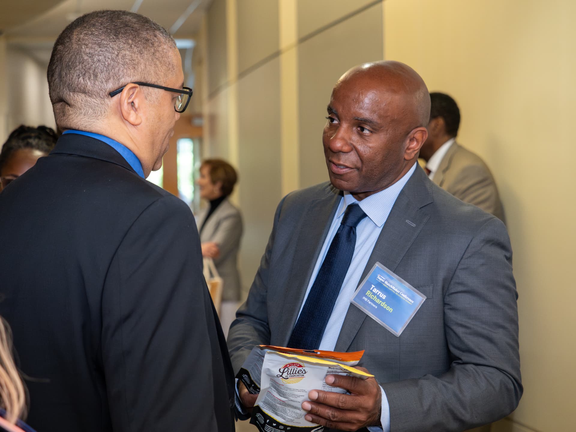 Two men in suits talking in a hallway during a matchmaker conference
