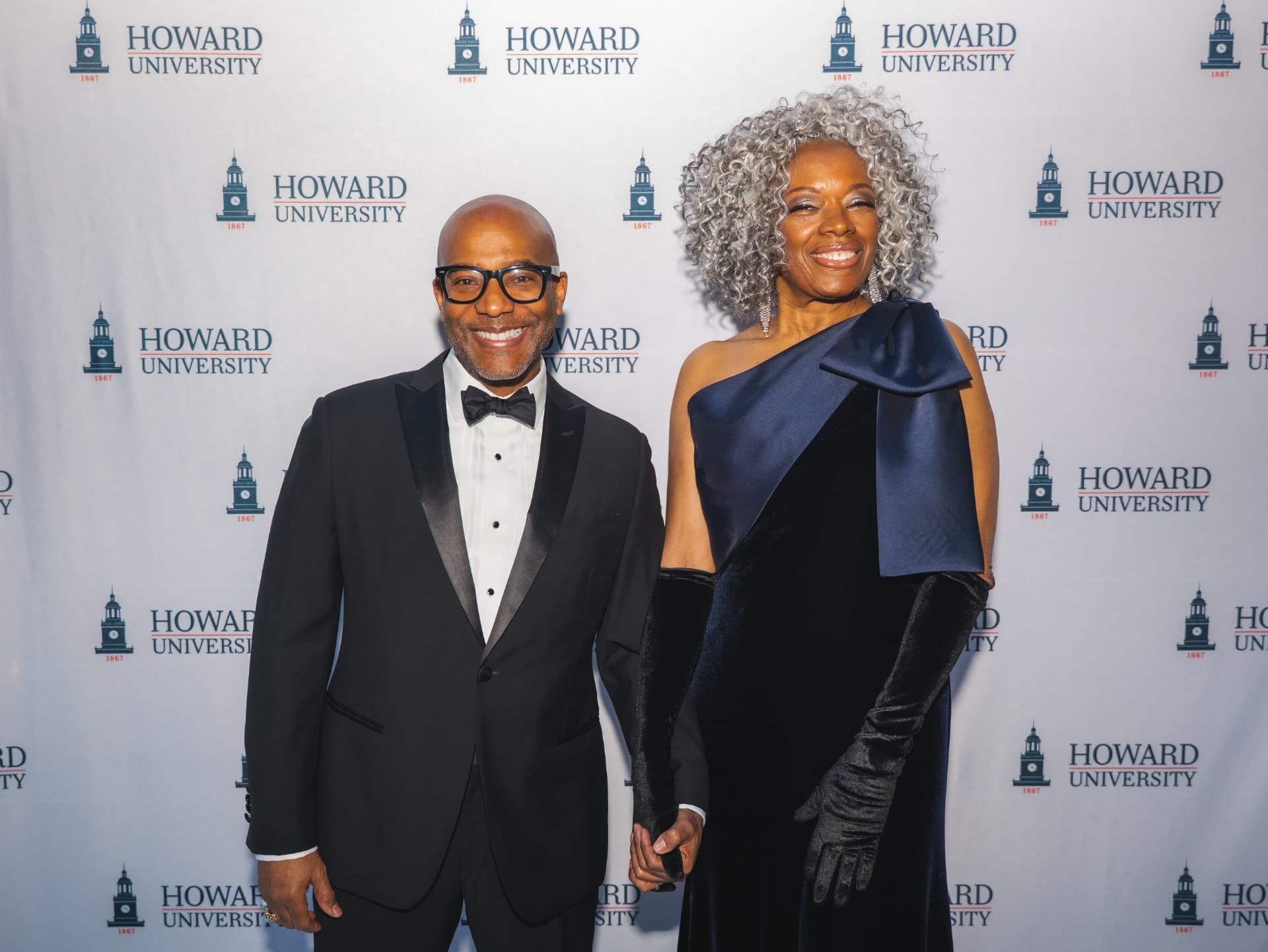 Couple holding hands on the Howard University step-and-repeat